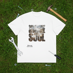 White t-shirt with 'Struggle for the Soul' graphic on grass with tools around