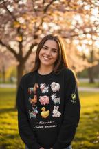 Woman wearing a black sweatshirt with animal illustrations in a park with cherry blossoms.