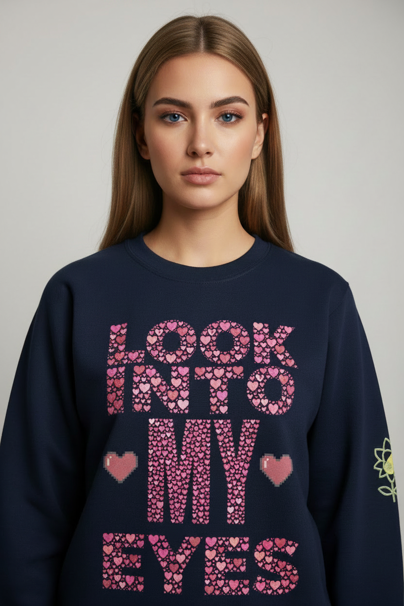 Woman wearing a navy blue sweatshirt with pink text and heart designs on a plain background