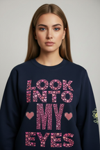 Woman wearing a navy blue sweatshirt with pink text and heart designs on a plain background