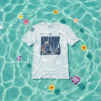 A white short-sleeve graphic T-shirt laid flat on turquoise water with floating flowers. The shirt has a large Aquarius zodiac-themed graphic on the front with the word AQUARIUS in dark blue and a zodiac illustration.