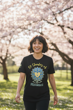 Person wearing a black t-shirt with a colorful design and text, standing in a park with cherry blossom trees.