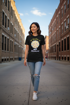 Woman wearing a black t-shirt with a logo and text, walking down a city street.