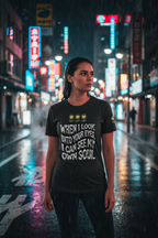 Person wearing a black t-shirt with text in a neon-lit city street